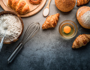 Freshly baked bread on wooden table,Bakery Concept- gold rustic crusty loaves of bread and buns on black chalkboard background. captured from above (top view, flat lay. Layout with copy space.