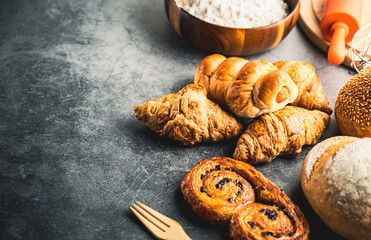 Freshly baked bread on wooden table,Bakery Concept- gold rustic crusty loaves of bread and buns on black chalkboard background. captured from above (top view, flat lay. Layout with copy space.