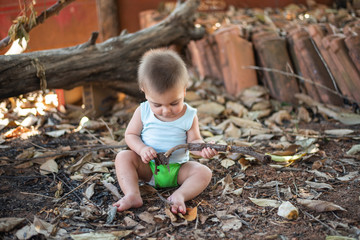 Blue-eyed baby sitting on the backyard ground