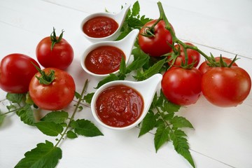 Tomato Sauce.Homemade tomato sauce in a white sauce-pan set and fresh ripe tomatoes with leaves on a white  background.