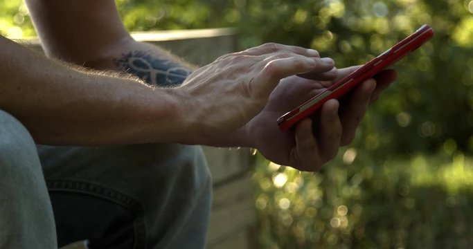 Man with tattoos swiping on smartphone.