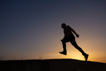 Obraz na płótnie Canvas silhouette of man running at sunrise