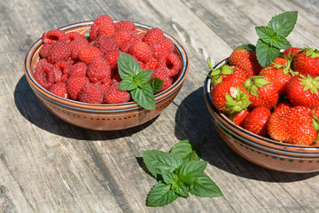 Two clay cups with berries strawberries,raspberries and sprigs of green mint