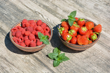 Two clay cups with berries strawberries,raspberries and sprigs of green mint