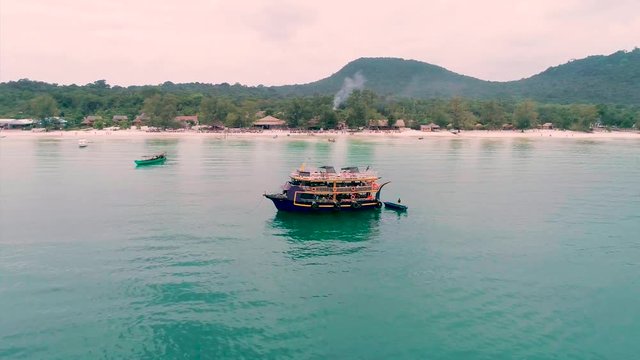 Aerial view of party on boat. drone flying around boat on beach. skyline, coastline on background. Circle shoot from drone. Koh Rong Island, Cambodia. Royalty high quality free stock footage.