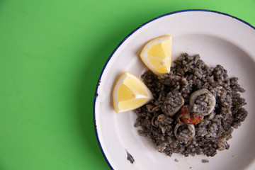 Plate of black rice with squid and prawns or Valencian black paella