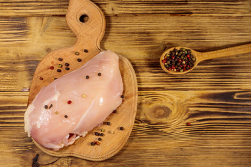 Raw chicken breast on cutting board on wooden table