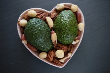Avocados and nuts. Two ripe avocados, pecans, brazil nuts and macadamia nuts in a heart shape dish...