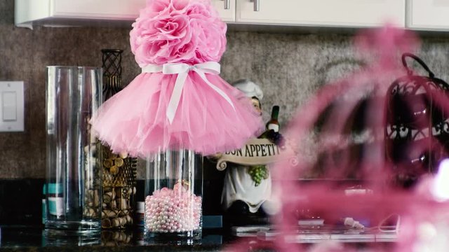 PULL FOCUS: Centerpiece crafted with pink pearls baby princess girl and tu-tu over glass vase.