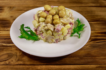 Potato salad with marinated mushrooms, sausage, onion and mayonnaise on wooden table