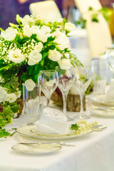 Valentines party dinner table setting with tableware and silverware and glasses set and Candlestick and flower in restaurant.