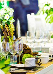 Valentines party dinner table setting with tableware and silverware and glasses set and Candlestick and flower in restaurant.