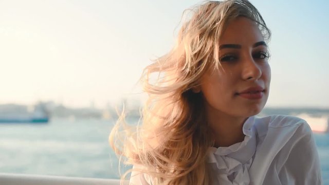 Slow Motion:Beautiful girl enjoys moment while cruising with view of sea on background.Traveler concept