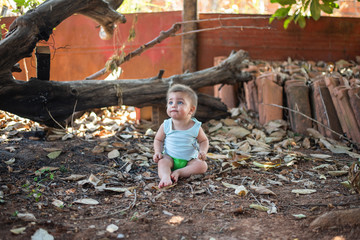 Blue-eyed baby sitting on the backyard ground