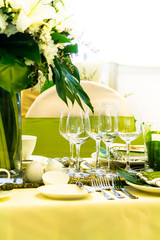 Christmas party dinner table setting with tableware and silverware and glasses set and Candlestick and flower in restaurant.