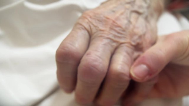 Young Person With Tears Confronting Elderly Dying Person. Last Goodbye, At The Hospital Bed. Point Of View Shot , Partially Blurred To Show Tears