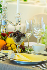Christmas party dinner table setting with tableware and silverware and glasses set and Candlestick and flower in restaurant.