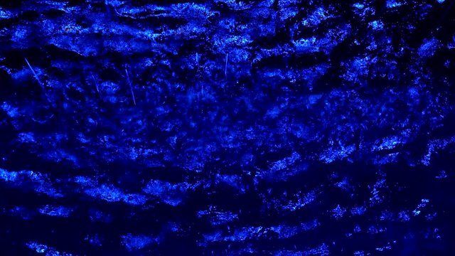 A decorative waterfall is shown indoors up close, illuminated by blue light.