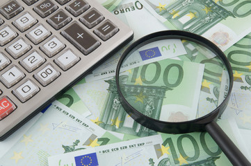 Business concept, calculator and magnifying glass on euro banknotes