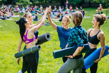 Group of five fit happy women giving high five in park after workout,celebrating success.Setting...