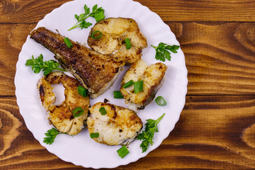Roasted pollock in white plate on a wooden table