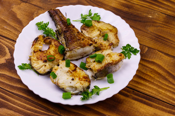 Roasted pollock in white plate on a wooden table
