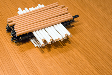 Bundle of paper straws white, brown and black in a wood table display background, great for environmental purpose