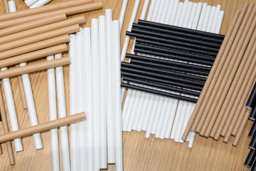 Bundle of paper straws white, brown and black in a wood table display background, great for environmental purpose