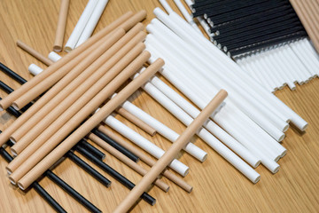 Bundle of paper straws white, brown and black in a wood table display background, great for environmental purpose