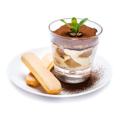 Classic tiramisu dessert in a glass cup and savoiardi cookies on plate with spoon isolated on a white with clipping path