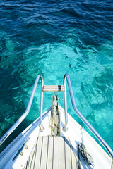Obraz premium (Selective focus) Stunning view of a bow of a yacht sailing on a beautiful turquoise and transparent sea. (Emerald Coast) Sardinia, Italy.