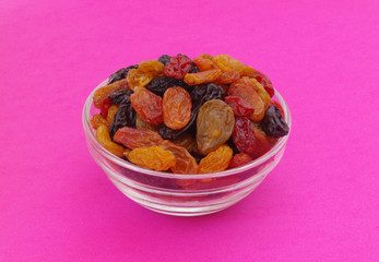 Raisins in glass bowl on pink background