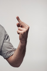 partial view of man showing middle finger isolated on grey, human emotion and expression concept