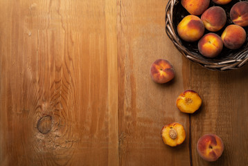 Fresh ripe peaches fruits in basket on wooden rustic background. Top view.
