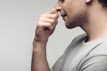 partial view of pensive man touching nose isolated on grey, human emotion and expression concept