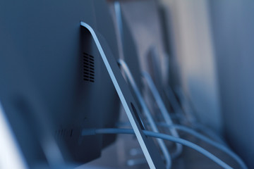 row of desktop computers with cables on desk
