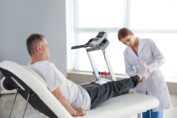 Physiotherapist working with mature patient in rehabilitation center