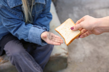 Woman giving food to homeless little girl outdoors