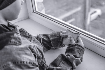 Homeless little boy with bread near window indoors