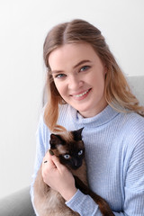 Young woman with cute Thai cat sitting in armchair