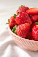 Bowl with ripe strawberry on table, closeup