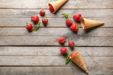 Sweet ripe strawberry and waffle cones on wooden background