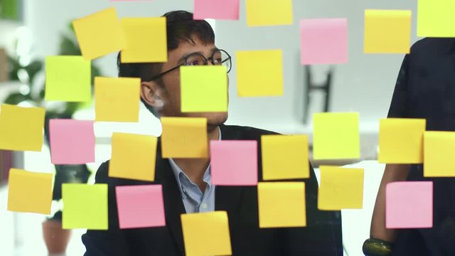 Group of Asian creative men workshop and brainstorm in front of mirror board. Young professional business team working create strategy, business situation, startup in Loft office concept. Slow motion.