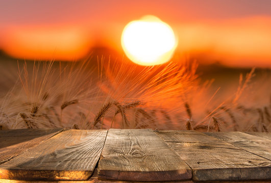 wood board table in front of field of wheat on sunset light. Ready for product display montage