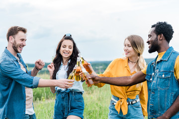 happy multicultural men and women clinking bottles with beer