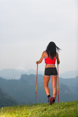 Sporty woman with nice body looks at the panorama in the mountains during on trekking