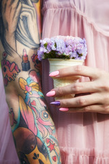 Beautiful flowers in the hands of a girl with tattoos, cosmetics. Summer flowers and bright makeup...