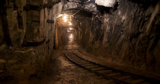 A dimly lit mining shaft. Water dripping onto the rails of the old mining cart.