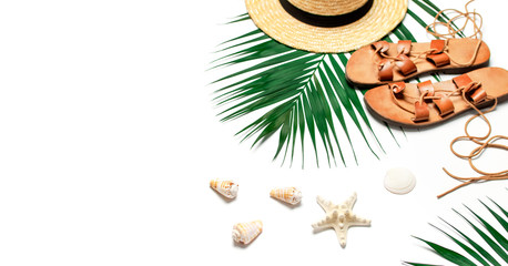 Woman's beach accessories flat lay. Straw hat, leather sandals, tropical palm leaves, seashells, starfish on white background. Top view copy space. Summer backdrop