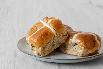 Hot cross buns piled on a green glazed plate with a grey wood background